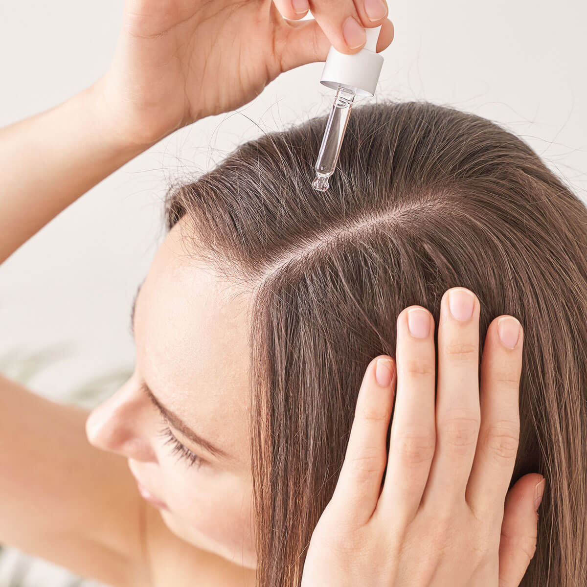 girl applying hair serum to scalp salon Toujours Belle